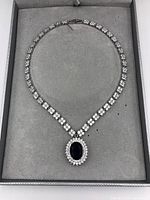 Full view of necklace laid flat in a gray box showing entire chain and pendant.