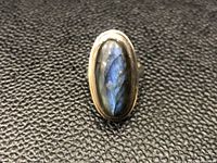 Front view of oval labradorite stone in sterling silver setting on black textured background.