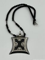 Full view of the sterling silver pendant necklace with black beads laid flat on a white background.