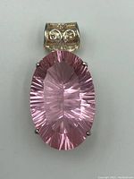 Full front view of the pendant showing the faceted oval pink gemstone and ornate silver bail.