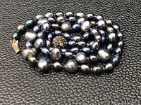 Close-up view of the Tahitian black pearls coiled, showing irregular shapes and sizes.