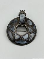 Front view showing the circular brooch with multiple gray and white agate stone inlays set in sterling silver with intricate engraved patterning.