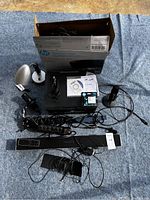 Overview of lot with HP DeskJet 3637 printer box, power strip, soundbar, power cords and cables on blue blanket.