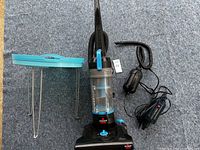 Photo showing Bissell PowerGlide vacuum, two electric air pumps with cords, and collapsing table's metal legs.