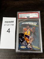 Front view of Kobe Bryant 'Never Compromise' basketball card graded PSA 7 NM with label showing date, card name, and grade.