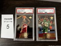 Front view of two graded 2003 Upper Deck LeBron James rookie cards in PSA slabs: one Mint 9 showing LeBron shooting in red jersey, one NM-MT+ 8.5 showing LeBron dribbling in green jersey.