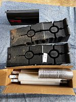 Pair of Rhino Ramps, dryer vent hose, and box containing shrink wrap rolls on a cloth.