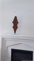 Full view of the metal art sculpture atop the clear resin base on a white mantelpiece with no background distractions.