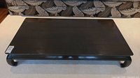 Top angle view of rectangular Asian-style black coffee table with rounded edges and curved legs.