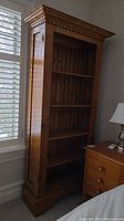 Frontal view of the tall amber pine bookcase showing five shelves and molded crown.