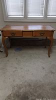 Full front view of the solid wood desk showing two drawers and decorative legs.