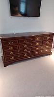 Full front view of dark wood 10 drawer Drexel dresser under wall-mounted TV