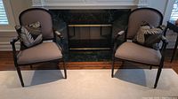 Pair of armchairs front view with two throw pillows in front of fireplace