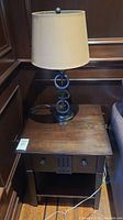 View of lamp on side table showing wood surface wear and lamp cord