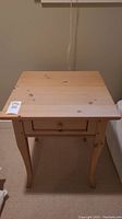 Front view of Lane solid wood side table showing rectangular top with scratches and drawer with wooden handle, supported by four curved legs.