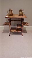 Full view of the tiered bamboo shelf with two brass teapots on top and side shelves extended.