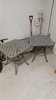 Pair of matching square metal patio tables side by side against wall