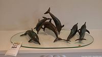 Oval glass plate with three bronze dolphin sculptures