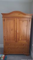 Front view of the solid wood wardrobe showing two paneled doors and three drawers at the bottom.