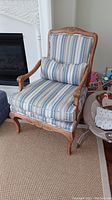 Front view of armchair showing striped cushions and carved wood frame