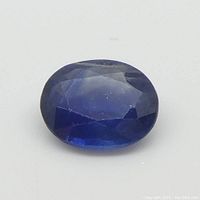 Close-up photo of oval blue sapphire gemstone, showing faceting and color.