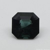 Straight-on view of the greenish-blue Asscher-cut tourmaline gemstone showing the symmetrical square shape and deep color.