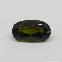 Close-up front angled view of the green oval tourmaline gemstone showing facets and color