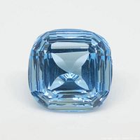 Front facing view of the blue topaz gemstone showing the cushion fantasy cut and the color tone.