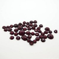 Photo showing scattered round rose cut garnet gems, dark red color, various sizes from small to medium.