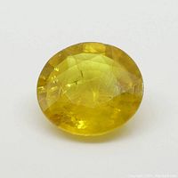 Top angle view of the round yellow sapphire displaying facets and color.