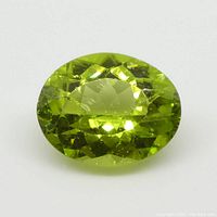 Clear close-up photo of the oval-shaped green peridot gemstone, showing facets and natural inclusions.