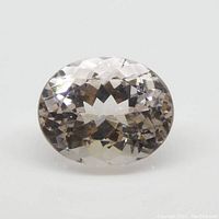 Clear oval shaped faceted morganite gemstone displayed on white background, showing internal facets and light pink color.