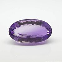Clear top-down view of faceted oval amethyst with visible facets and purple color on a white background.