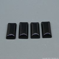 Four polished rectangular cabochon black onyx stones arranged in a row on a white background.