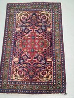 Full view of the rectangular Persian wool rug with intricate central medallion and detailed border patterns in traditional colors.