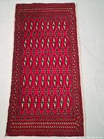 Full view of the rectangular hand knotted wool rug with geometric repeating motifs and multiple borders.