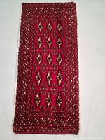 Full view of hand knotted wool Turkman rug showing detailed geometric pattern and vibrant red color.