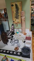 Wide shot capturing the full assortment of decorative items on a white surface, including the tall wood carved incense holder, metal candle holders, glass tray, and other smaller items.
