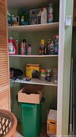 Shelf with assorted used cleaning supplies including sprays, liquid bottles, and cans