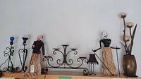 Wide image showing all items: metal candle holder, two puppets, small lamp, flower lamp
