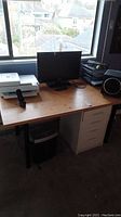Desk setup showing Toshiba TV, Logitech speaker, file stacker, and printer on a wooden desk near window.