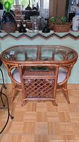 Front view of oval rattan table with glass top and two matching chairs