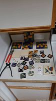 Tiles and tile cutters arranged on a countertop showing various decorative tile sizes and patterns plus two metal tile cutting tools.