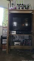 Wide view showing TV in cabinet with Yamaha amplifier, DVD player, and collection of DVDs and CDs on shelves and beside cabinet
