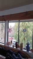 Photo showing the line-up of six vases on the window sill and two windchimes hanging near the window.