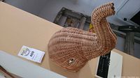 Wicker elephant head viewed from side showing woven wicker material and upward curved trunk.