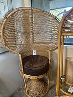 Front view of wicker peacock chair with round brown cushion and pedestal base