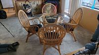 Four wicker chairs surrounding round glass-topped wicker table, set view