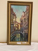 Vertical oil painting in gold decorative frame showing Venetian canal with buildings, bridge, gondolas.