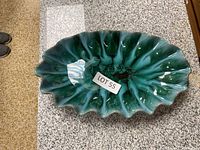 Top and angled views of Blue Mountain ceramic art pottery bowl with shell-like form and mottled blue-green glaze.